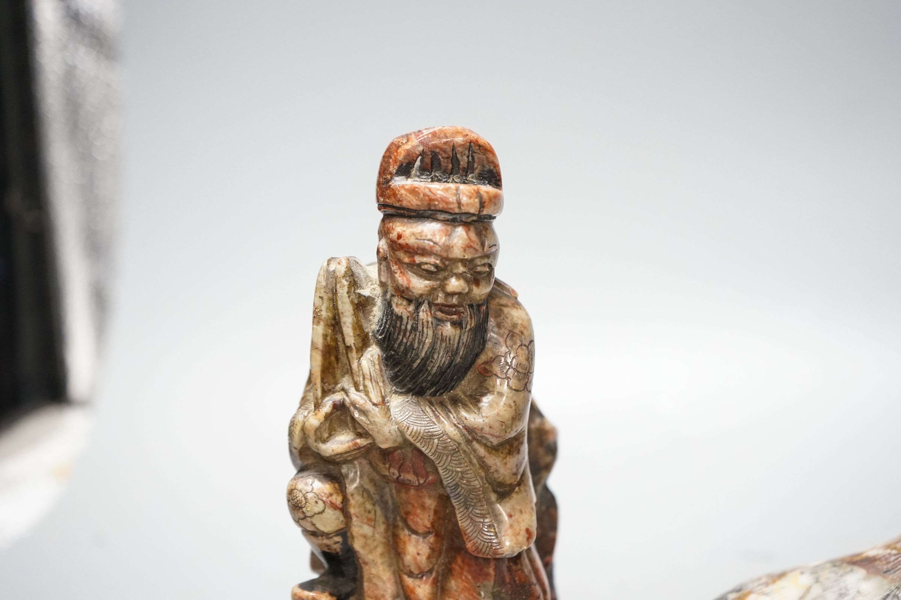A pair of Chinese soapstone figures of immortals, modelled seated on rocky bases and a similar figure of tiger, 12cm